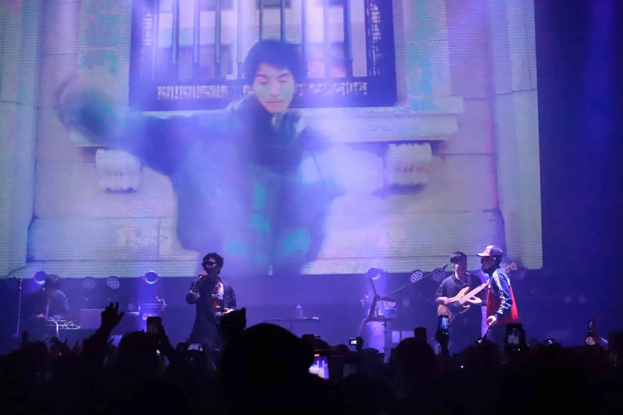 青紫の照明の中、LEDビジョンにアーティストの姿を大写しにしたステージ